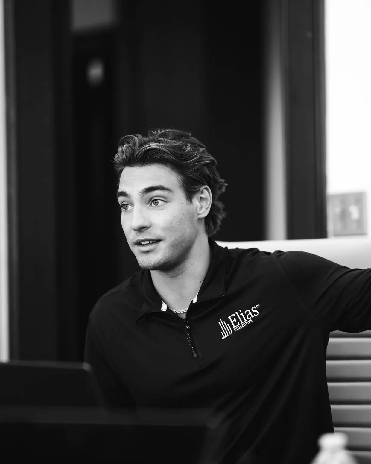 Addison Moore mid-conversation at a meeting table, wearing an Elias Collective quarter-zip